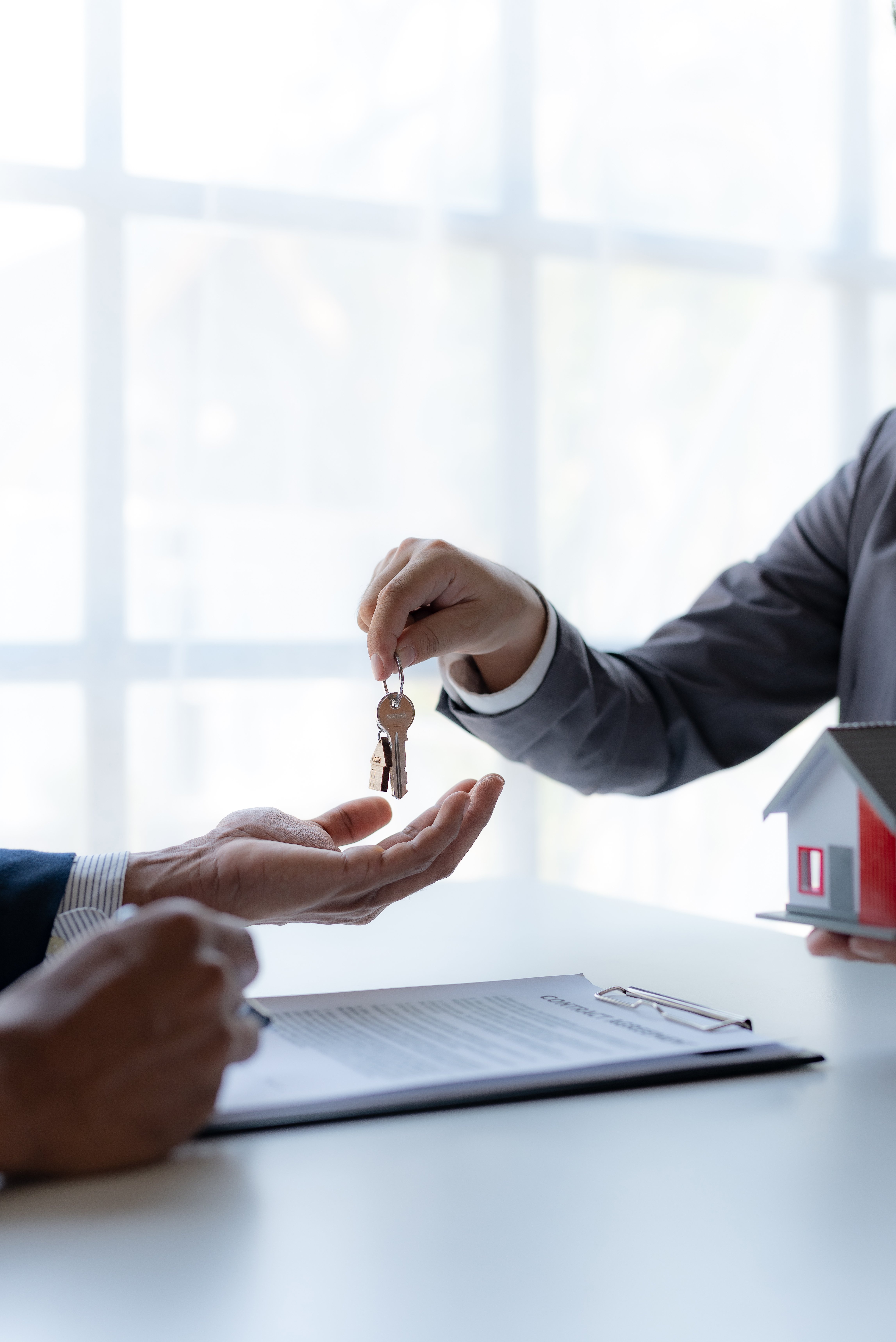 Real estate agent giving house key to the client after signing the real estate contract. Home and real estate trading concept.