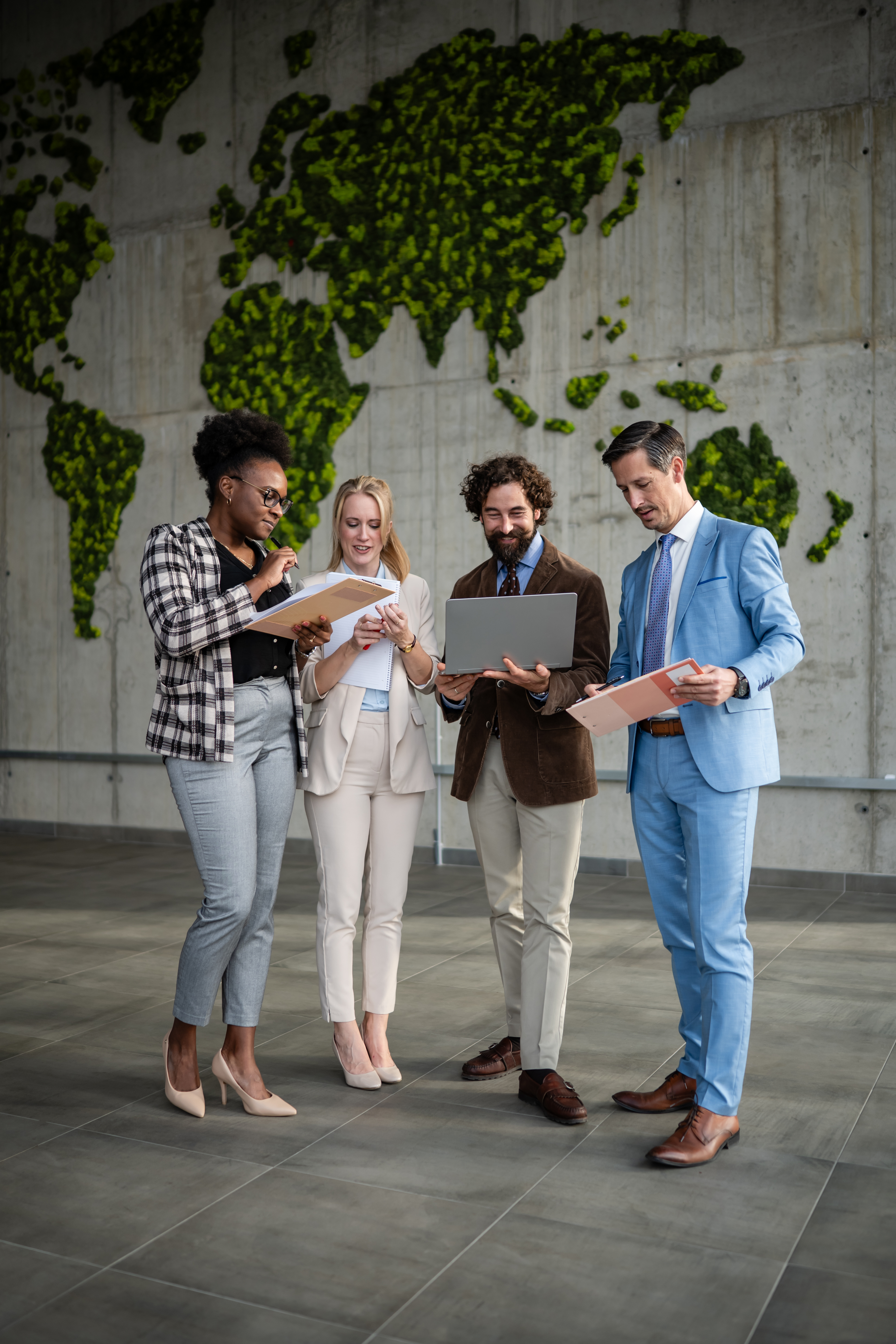 Professionals discussing work and global environmental impact in a modern office with a green world map on the wall